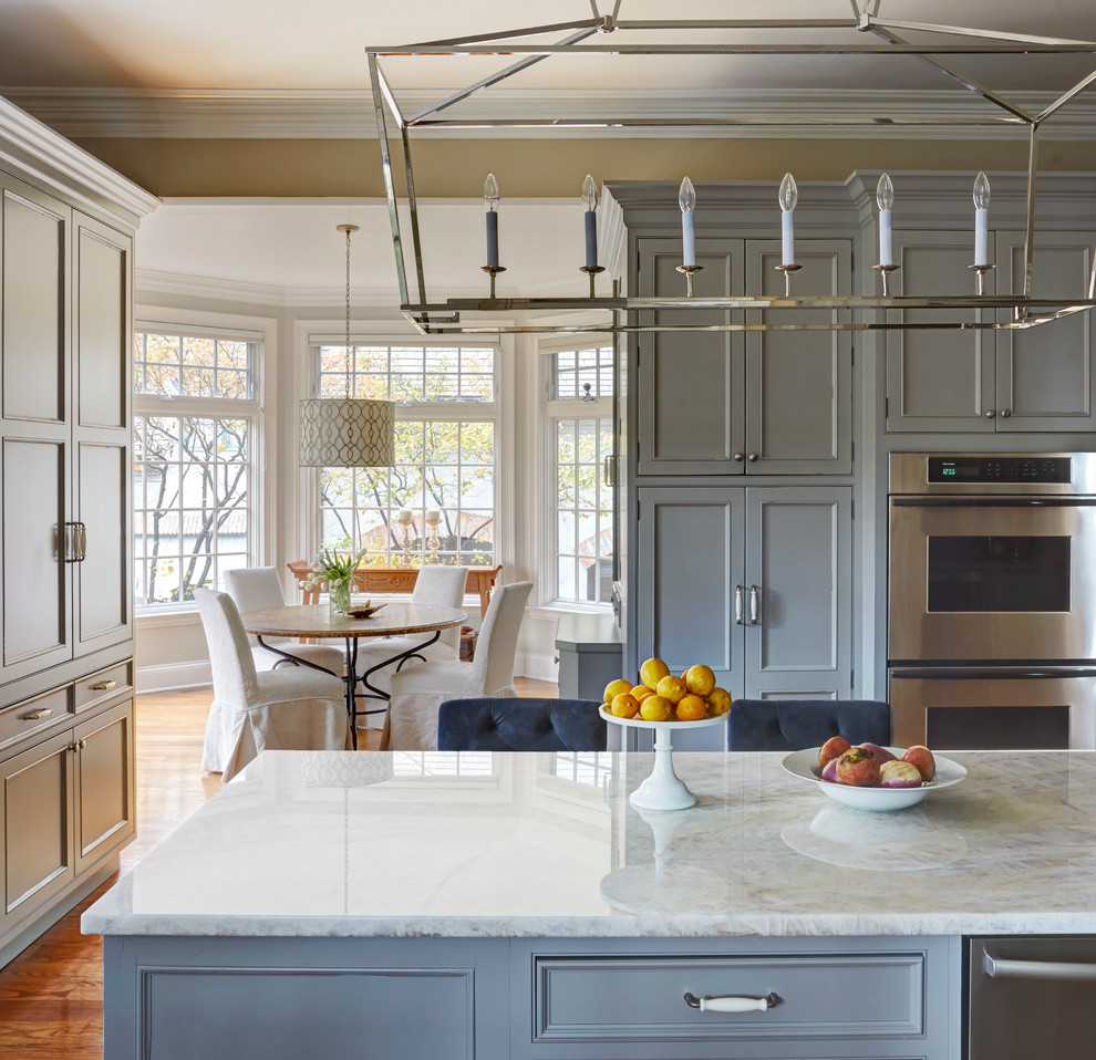 Design ideas for a mid-sized transitional u-shaped separate kitchen in Chicago with a farmhouse sink, recessed-panel cabinets, grey cabinets, quartzite benchtops, white splashback, subway tile splashback, stainless steel appliances, medium hardwood floors and with island.