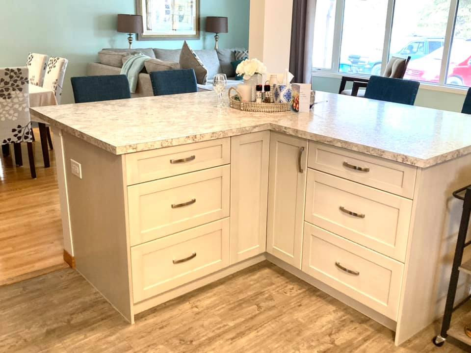 Mid-sized transitional l-shaped vinyl floor and beige floor open concept kitchen photo with a drop-in sink, shaker cabinets, beige cabinets, laminate countertops, gray backsplash, ceramic backsplash, stainless steel appliances, an island and multicolored countertops