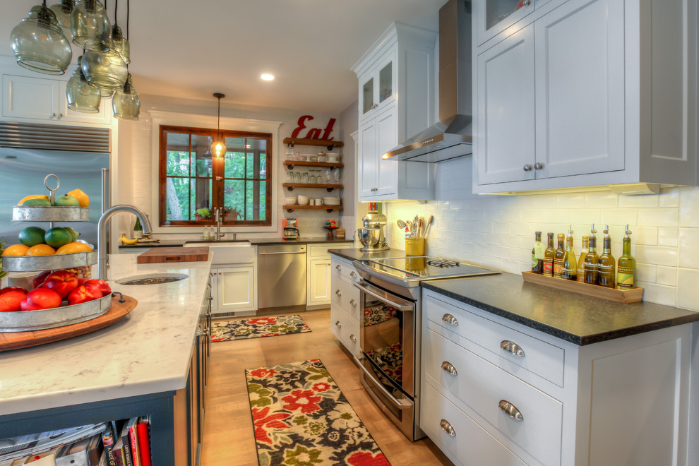 Kennedy Lake House - Inspiration for a mid-sized cottage kitchen remodel in Grand Rapids with a farmhouse sink, shaker cabinets, white cabinets, white backsplash, stainless steel appliances and an island