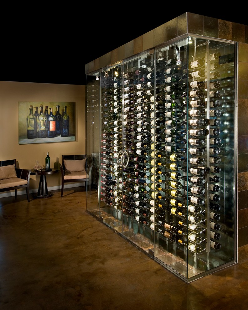This is an example of a mid-sized contemporary wine cellar in Phoenix with display racks, concrete floors and brown floor.