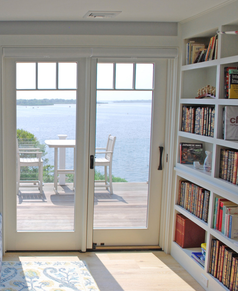 Idee per un grande studio stile marinaro con libreria e parquet chiaro