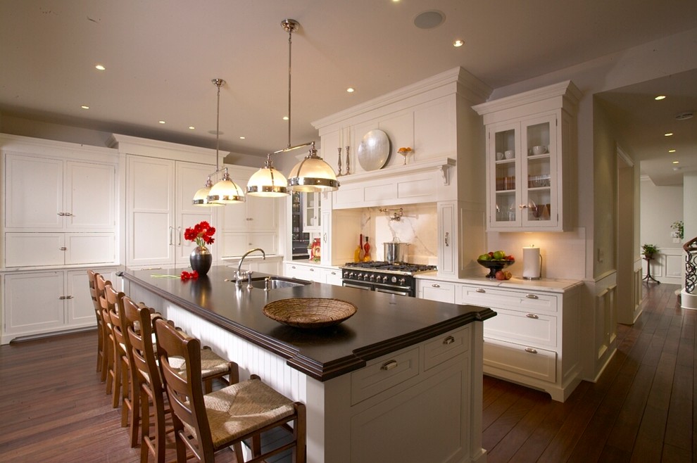 Example of a transitional dark wood floor kitchen design in Chicago with an undermount sink, shaker cabinets, white cabinets, marble countertops, white backsplash and paneled appliances