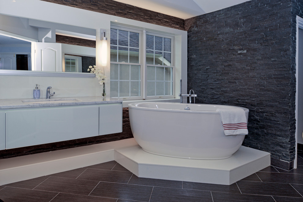 Large contemporary master bathroom in Other with an undermount sink, flat-panel cabinets, white cabinets, a freestanding tub, gray tile, stone tile, grey walls, porcelain floors, marble benchtops and grey floor.