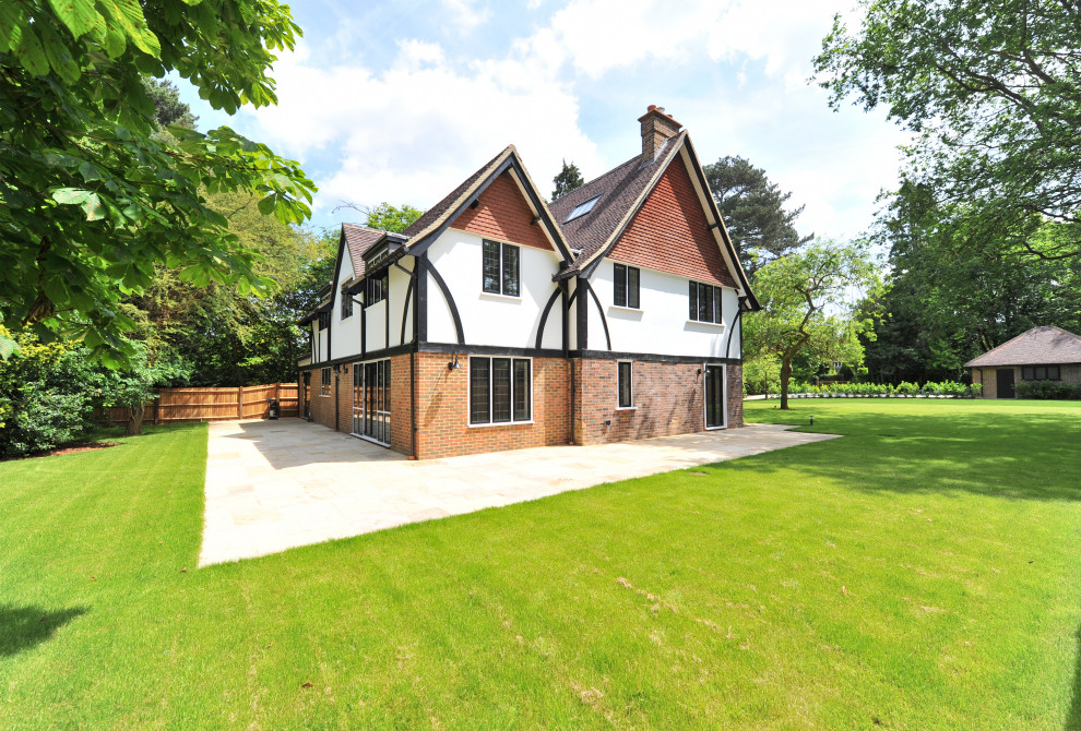 Large and white traditional detached house in Surrey with three floors, a pitched roof, a tiled roof and a brown roof.
