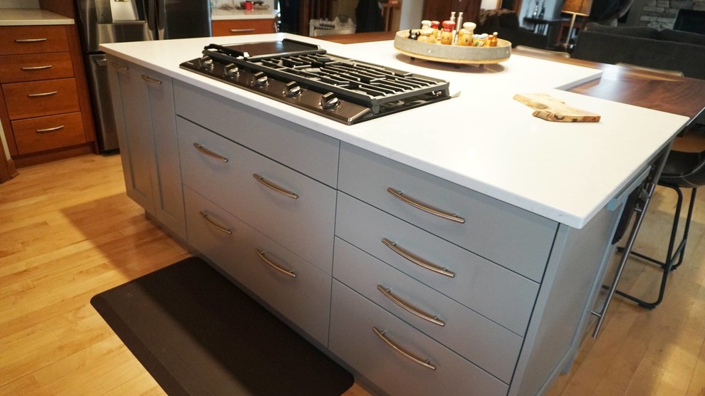 Inspiration for a large transitional l-shaped medium tone wood floor open concept kitchen remodel with an undermount sink, recessed-panel cabinets, brown cabinets, white backsplash, subway tile backsplash, stainless steel appliances, an island and white countertops