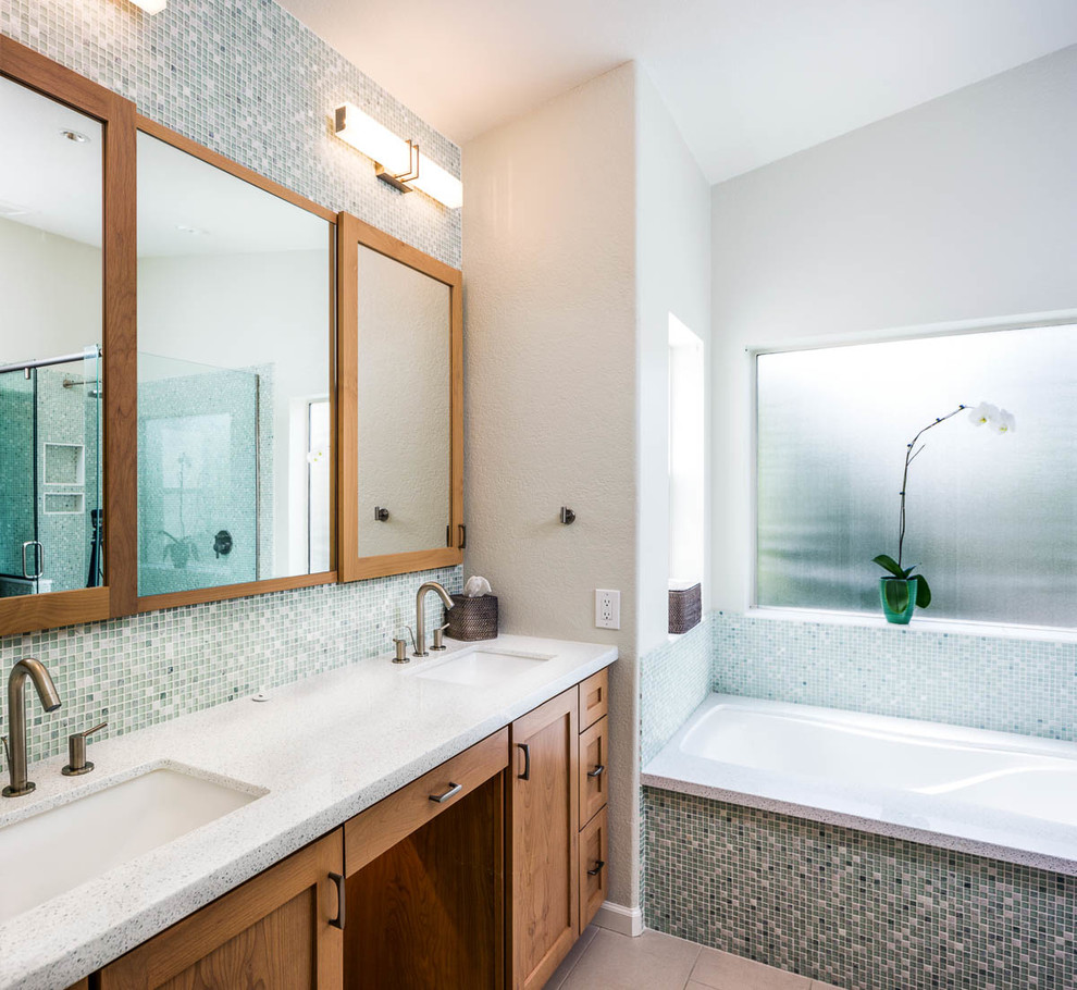 This is an example of a mid-sized modern master bathroom in Phoenix with shaker cabinets, light wood cabinets, an undermount tub, a one-piece toilet, mosaic tile, beige walls, porcelain floors, an undermount sink, engineered quartz benchtops, green tile, blue tile, white tile and beige floor.