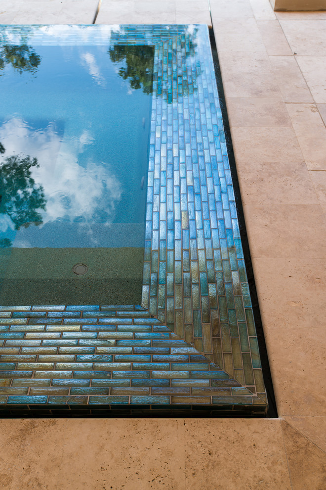 Inspiration for a large transitional backyard rectangular infinity pool in Houston with a hot tub and natural stone pavers.