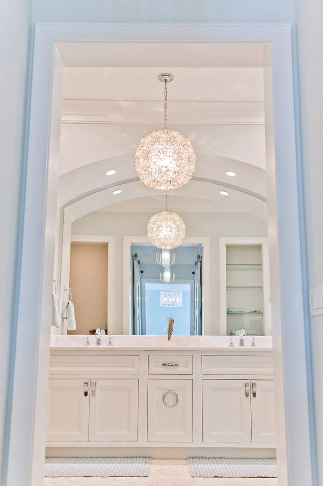 Inspiration for a mid-sized beach style master bathroom in Jacksonville with beaded inset cabinets, white cabinets, white tile, glass sheet wall, white walls, pebble tile floors and marble benchtops.