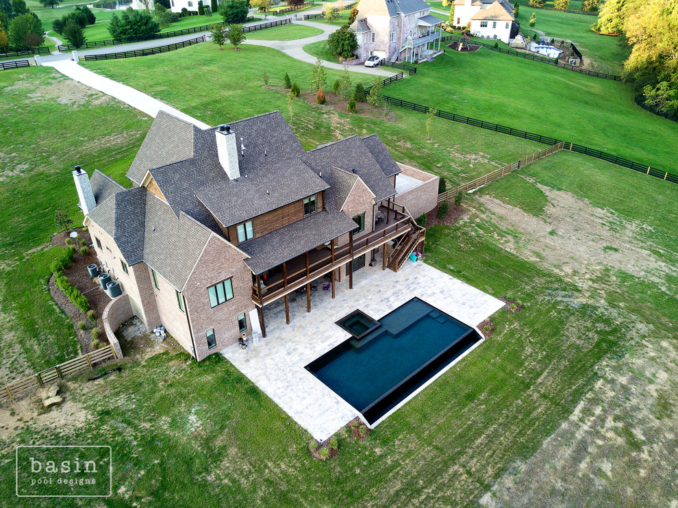 Example of a large transitional backyard stone and custom-shaped infinity hot tub design in Nashville