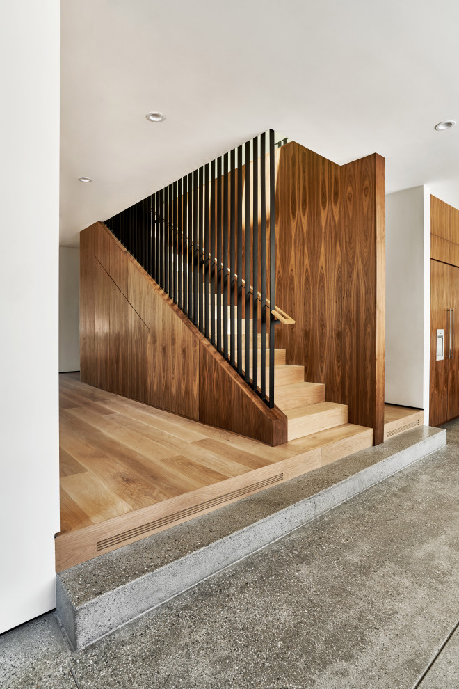 Свежая идея для дизайна: прямая деревянная лестница среднего размера в современном стиле с деревянными ступенями, перилами из смешанных материалов и панелями на части стены - отличное фото интерьера