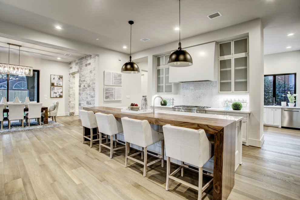 Design ideas for an expansive contemporary galley kitchen in Houston with a submerged sink, shaker cabinets, grey cabinets, engineered stone countertops, white splashback, stainless steel appliances, medium hardwood flooring, multiple islands, brown floors and grey worktops.