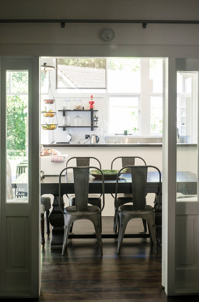 Example of a mid-sized transitional dark wood floor and brown floor kitchen/dining room combo design with metallic backsplash, white walls and no fireplace