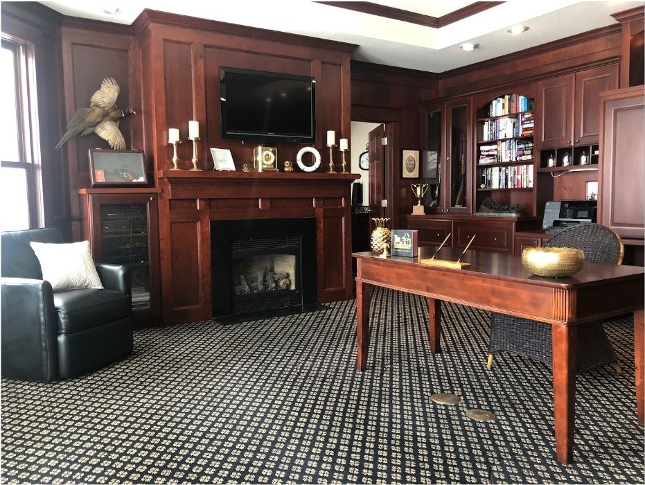 Inspiration for a large transitional study room in Minneapolis with brown walls, carpet, a standard fireplace, a wood fireplace surround, a built-in desk and multi-coloured floor.