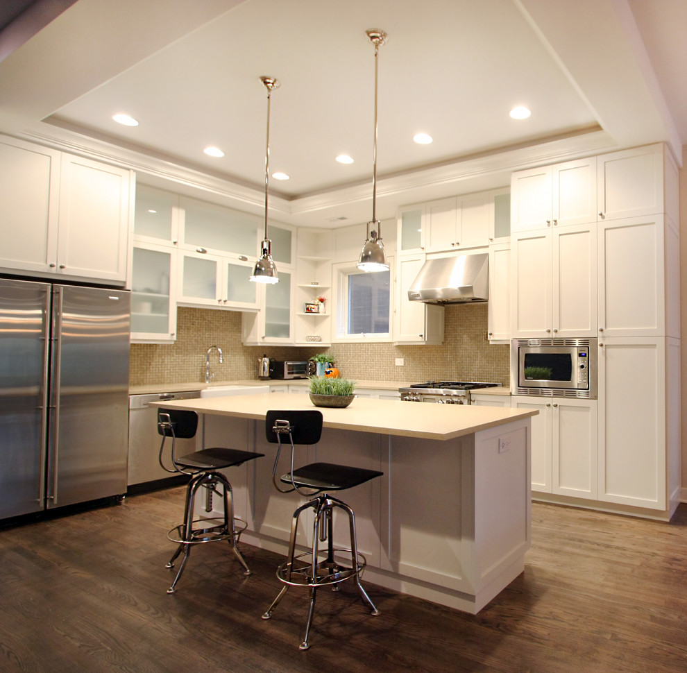 Inspiration for a transitional l-shaped medium tone wood floor eat-in kitchen remodel in Chicago with a farmhouse sink, shaker cabinets, white cabinets, quartzite countertops, beige backsplash, stainless steel appliances, mosaic tile backsplash and an island