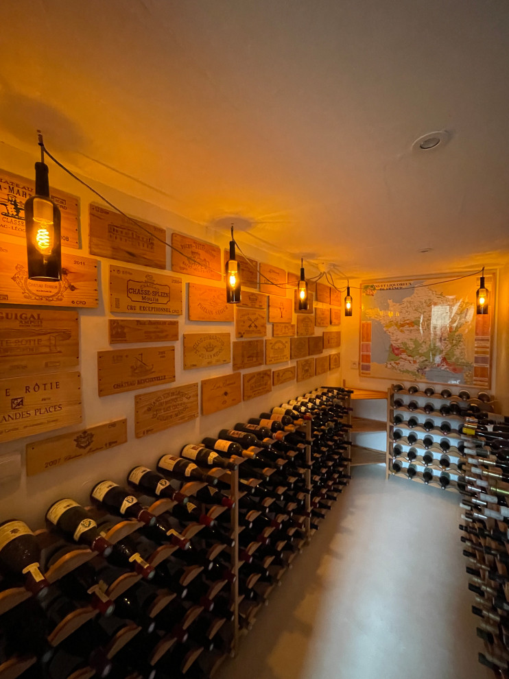 Mid-sized modern wine cellar in Other with concrete floors, display racks and white floor.