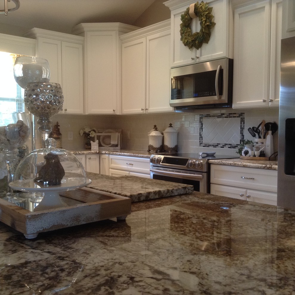 Mid-sized transitional l-shaped medium tone wood floor and brown floor eat-in kitchen photo in Orlando with a farmhouse sink, recessed-panel cabinets, white cabinets, granite countertops, white backsplash, subway tile backsplash, stainless steel appliances and an island
