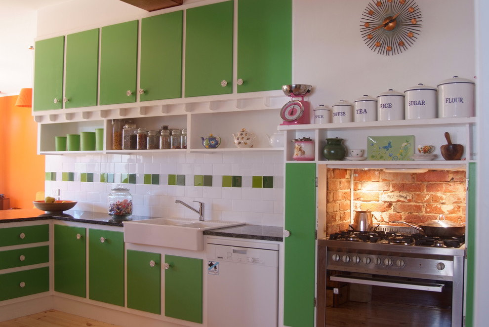 Eat-in kitchen - mid-sized eclectic l-shaped light wood floor eat-in kitchen idea in Adelaide with a farmhouse sink, raised-panel cabinets, green cabinets, granite countertops, black backsplash, porcelain backsplash, stainless steel appliances and no island
