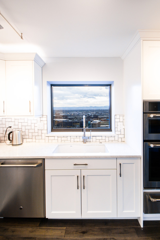 Example of a large transitional l-shaped medium tone wood floor eat-in kitchen design in Denver with an undermount sink, shaker cabinets, white cabinets, quartz countertops, multicolored backsplash, mosaic tile backsplash, stainless steel appliances, an island and white countertops