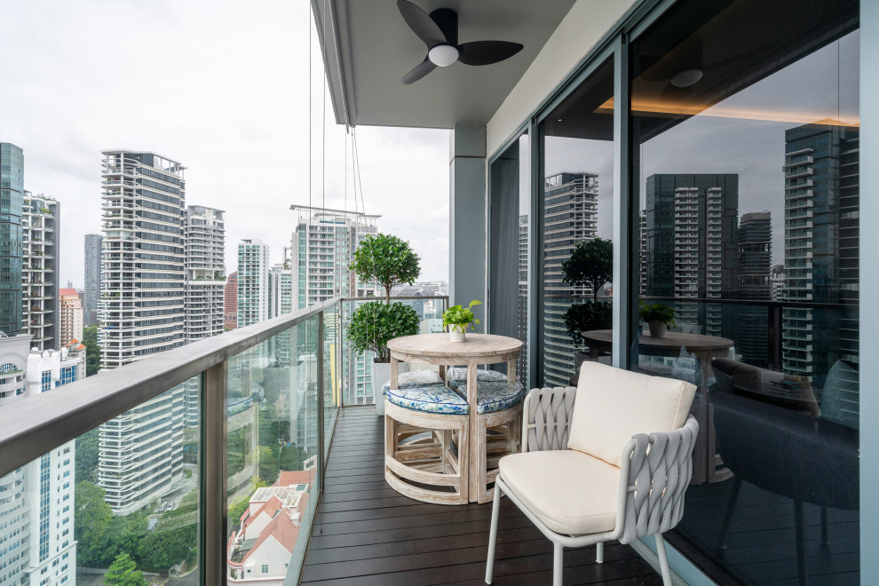 Contemporary balcony in Singapore with a roof extension and glass railing.