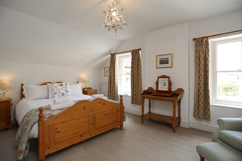 Mid-sized traditional master bedroom in London with white walls, carpet, no fireplace and beige floor.