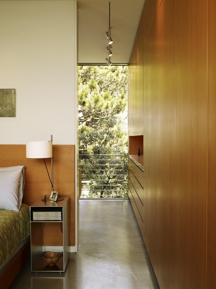 This is an example of a mid-sized contemporary master bedroom in San Francisco with concrete floors and white walls.
