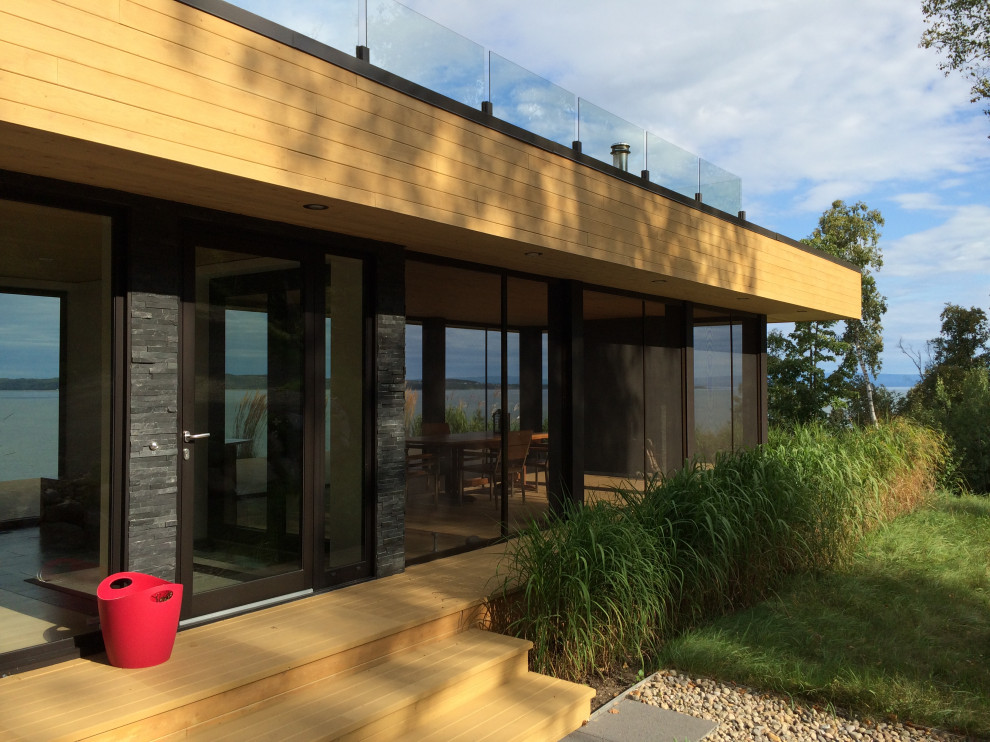 Diseño de fachada de casa beige moderna con revestimiento de madera, tejado plano y tablilla