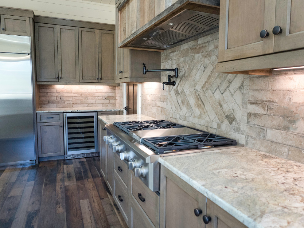 Country kitchen in Charlotte with a farmhouse sink, medium wood cabinets, granite benchtops, beige splashback, subway tile splashback, stainless steel appliances, with island, multi-coloured floor and beige benchtop.