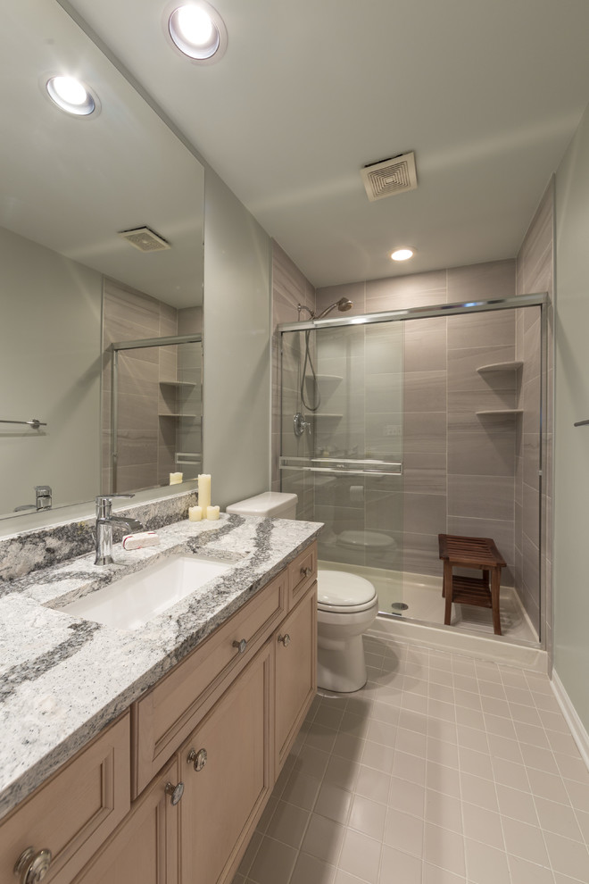 Photo of a mid-sized contemporary 3/4 bathroom in Chicago with flat-panel cabinets, medium wood cabinets, a drop-in tub, an alcove shower, a one-piece toilet, cement tiles, an undermount sink, limestone benchtops, beige tile, travertine and green walls.
