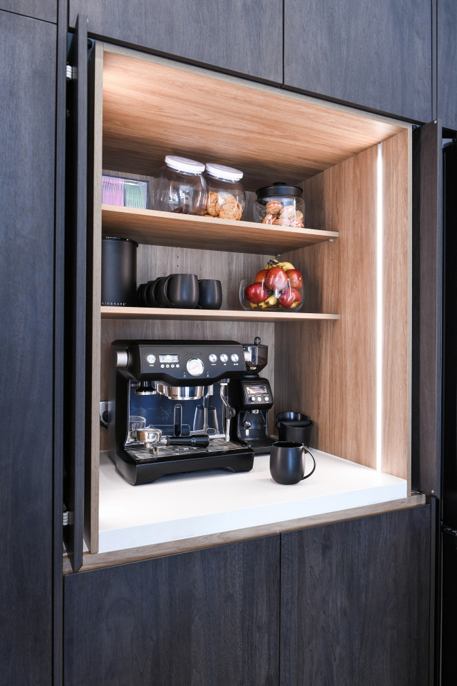 Design ideas for a mid-sized contemporary galley kitchen pantry in Sydney with a drop-in sink, dark wood cabinets, quartz benchtops, multi-coloured splashback, mirror splashback, black appliances, with island and white benchtop.