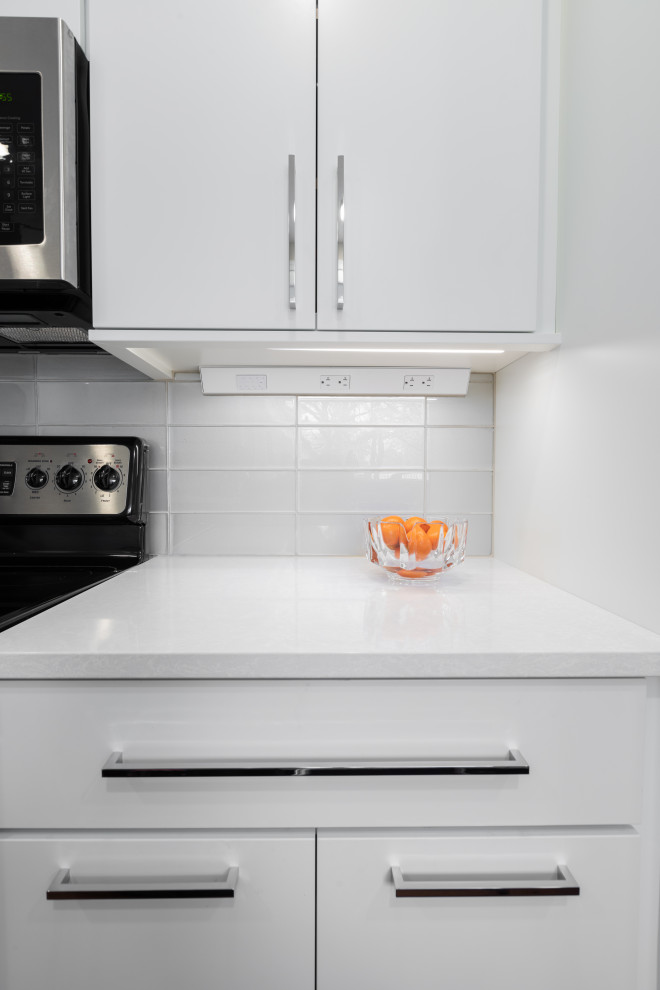 Eat-in kitchen - small 1950s galley eat-in kitchen idea with an undermount sink, white cabinets, quartz countertops, beige backsplash, glass tile backsplash, stainless steel appliances, no island and white countertops
