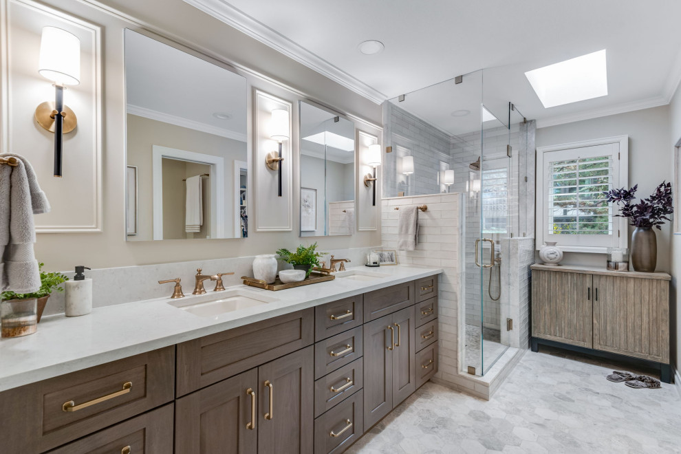 This is an example of a mid-sized traditional master bathroom in Denver with recessed-panel cabinets, brown cabinets, an alcove shower, a one-piece toilet, white tile, subway tile, beige walls, marble floors, an undermount sink, engineered quartz benchtops, white floor, a hinged shower door, white benchtops, a niche, a double vanity, a built-in vanity and panelled walls.