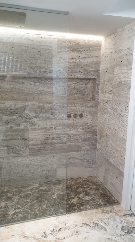 Cette image montre une salle de bain méditerranéenne avec un carrelage blanc, du carrelage en travertin, un mur blanc, un sol en travertin, un sol blanc et un mur en pierre.