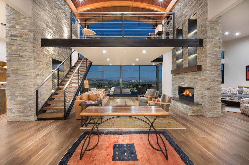 This is an example of a large contemporary open concept living room in Other with white walls, medium hardwood floors, a two-sided fireplace, a stone fireplace surround and brown floor.