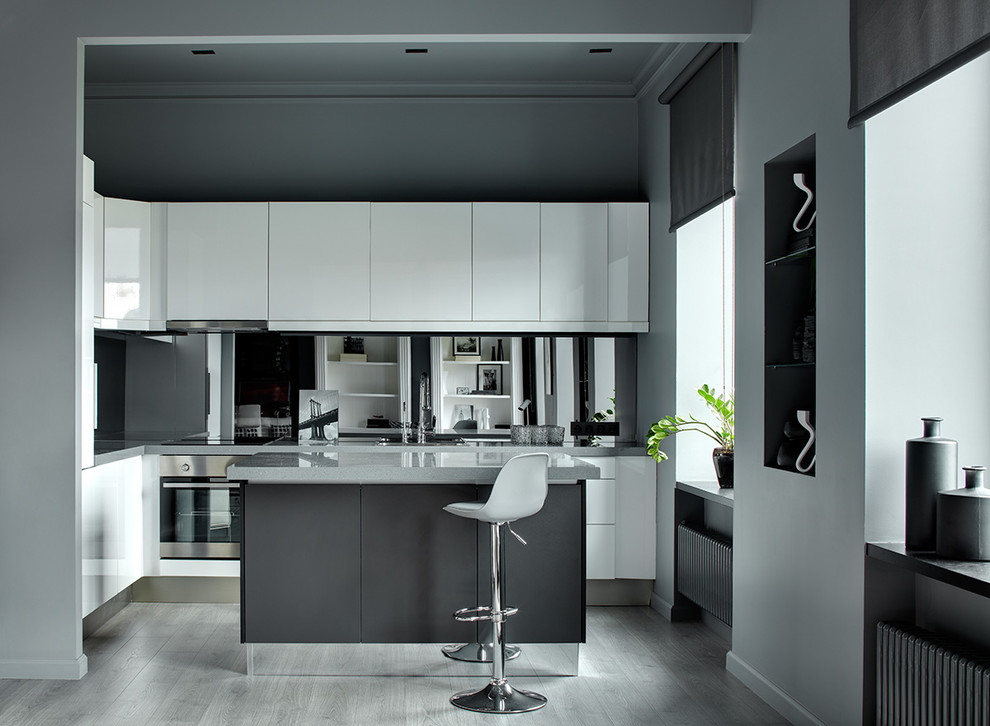 Contemporary l-shaped open plan kitchen in Moscow with flat-panel cabinets, white cabinets, glass sheet splashback, stainless steel appliances, light hardwood floors, with island, grey floor and grey benchtop.