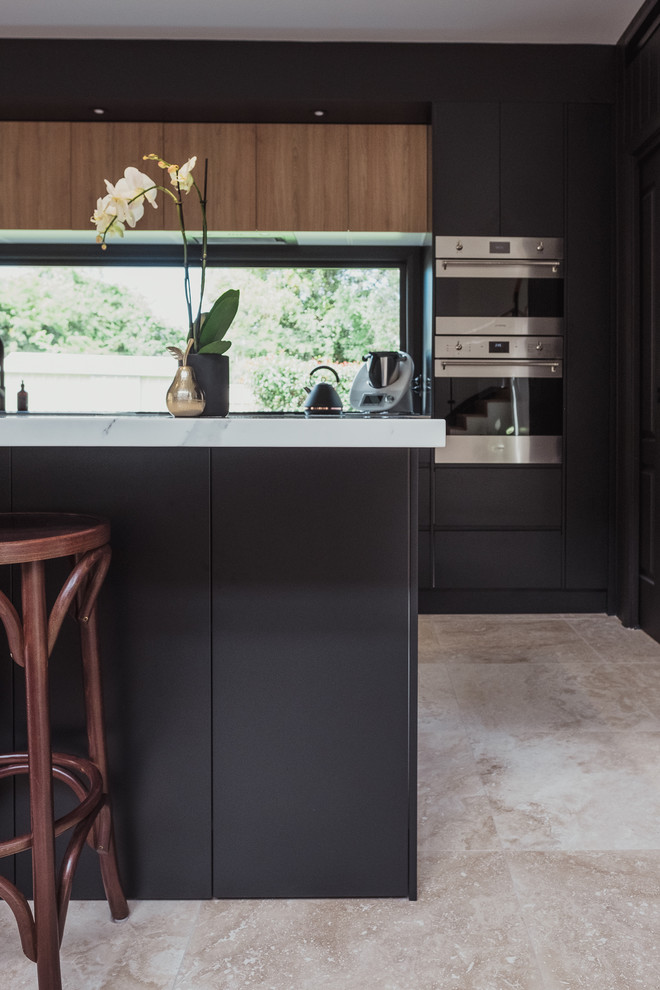 Photo of a mid-sized beach style galley eat-in kitchen in Central Coast with black cabinets, quartz benchtops, travertine floors, with island and white benchtop.