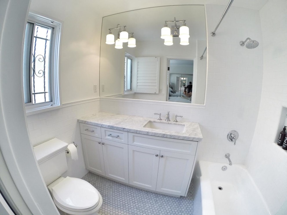 Inspiration for a mid-sized traditional bathroom in Los Angeles with an integrated sink, shaker cabinets, white cabinets, marble benchtops, an alcove tub, a one-piece toilet, white tile, subway tile, white walls and marble floors.