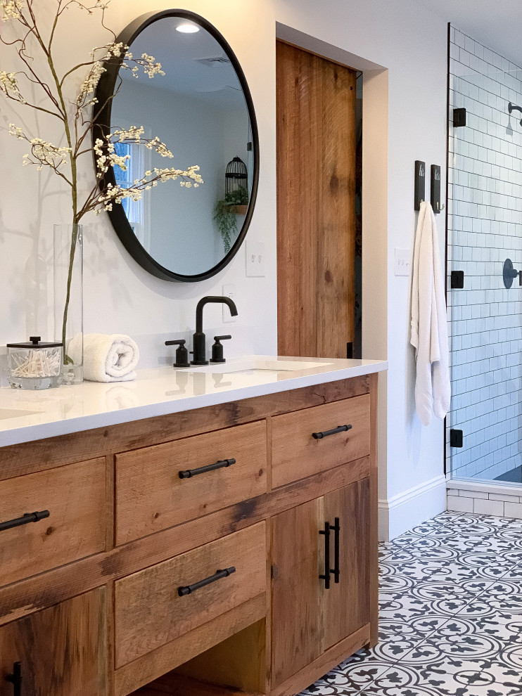 This is an example of a large transitional master bathroom in Philadelphia with medium wood cabinets, a corner shower, white tile, subway tile, white walls, an undermount sink, solid surface benchtops, multi-coloured floor, a hinged shower door, white benchtops and flat-panel cabinets.