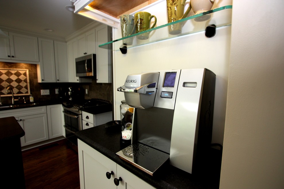 Inspiration for a mid-sized transitional l-shaped medium tone wood floor eat-in kitchen remodel in Raleigh with an undermount sink, shaker cabinets, white cabinets, granite countertops, gray backsplash, stone tile backsplash, stainless steel appliances and an island