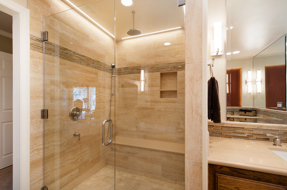 Inspiration for a large traditional master bathroom in Orange County with raised-panel cabinets, dark wood cabinets, an undermount tub, a curbless shower, a one-piece toilet, beige tile, glass tile, beige walls, travertine floors, an undermount sink and engineered quartz benchtops.