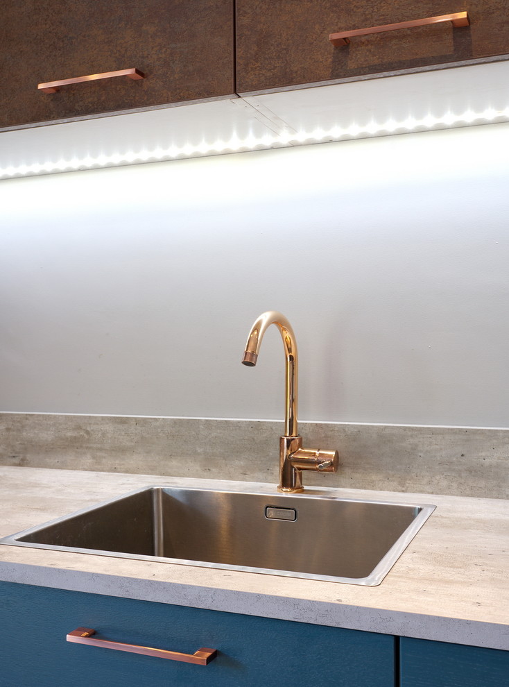 Inspiration for a medium sized contemporary l-shaped open plan kitchen with a built-in sink, flat-panel cabinets, green cabinets, tile countertops, grey splashback, wood splashback, stainless steel appliances, laminate floors, an island, brown floors and brown worktops.