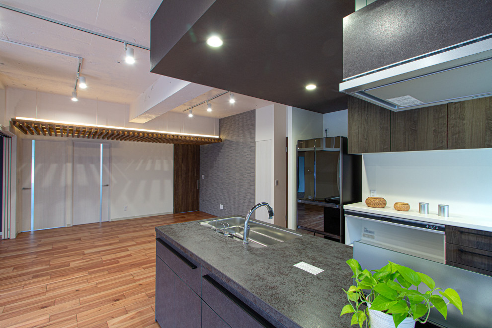 This is an example of a mid-sized industrial single-wall open plan kitchen in Other with an undermount sink, beaded inset cabinets, dark wood cabinets, stainless steel benchtops, white splashback, shiplap splashback, stainless steel appliances, dark hardwood floors, a peninsula, brown floor and recessed.