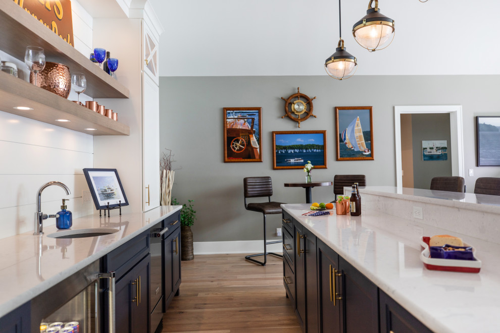 Example of a mid-sized beach style galley medium tone wood floor and brown floor wet bar design in Milwaukee with an undermount sink, flat-panel cabinets, white cabinets, quartz countertops, white backsplash, shiplap backsplash and white countertops