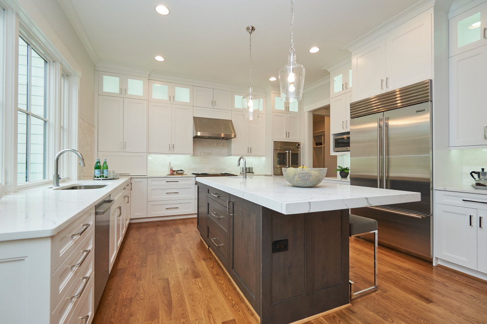 Large transitional u-shaped medium tone wood floor and brown floor eat-in kitchen photo in DC Metro with an undermount sink, shaker cabinets, white cabinets, quartz countertops, white backsplash, marble backsplash, stainless steel appliances, an island and white countertops