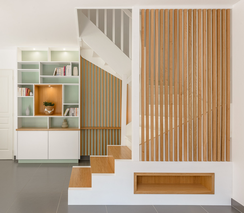 Small scandinavian wood u-shaped wood railing staircase in Lyon with painted wood risers, wood walls and under stair storage.