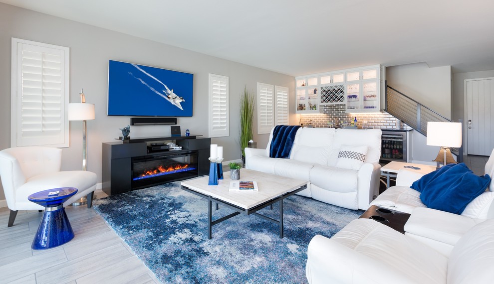 This is an example of a small modern open concept living room in Phoenix with grey walls, porcelain floors, a hanging fireplace, a wood fireplace surround, a wall-mounted tv and grey floor.