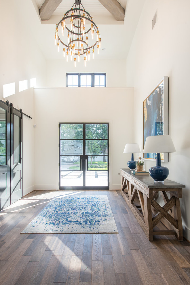 Photo of a large beach style foyer in Houston with white walls, medium hardwood floors, a double front door, a glass front door and brown floor.