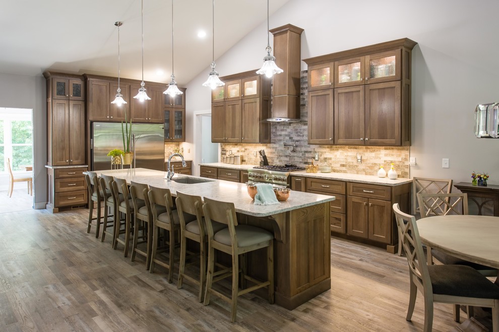 Example of a transitional l-shaped open concept kitchen design with an undermount sink, shaker cabinets, stainless steel appliances and an island