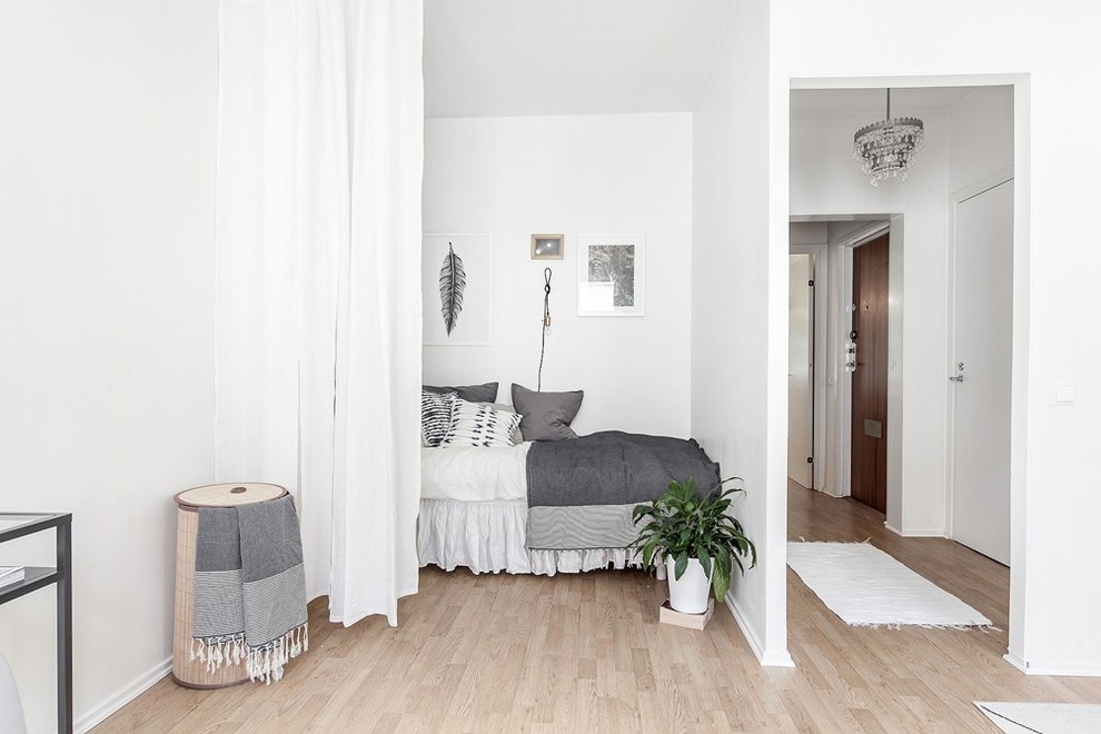 This is an example of a small scandinavian bedroom in Gothenburg with white walls, light hardwood floors and no fireplace.