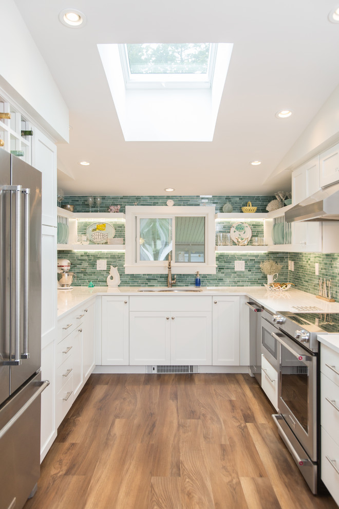 Photo of a small beach style u-shaped kitchen in Boston with an undermount sink, shaker cabinets, white cabinets, quartz benchtops, green splashback, stainless steel appliances, medium hardwood floors, no island, white benchtop and matchstick tile splashback.
