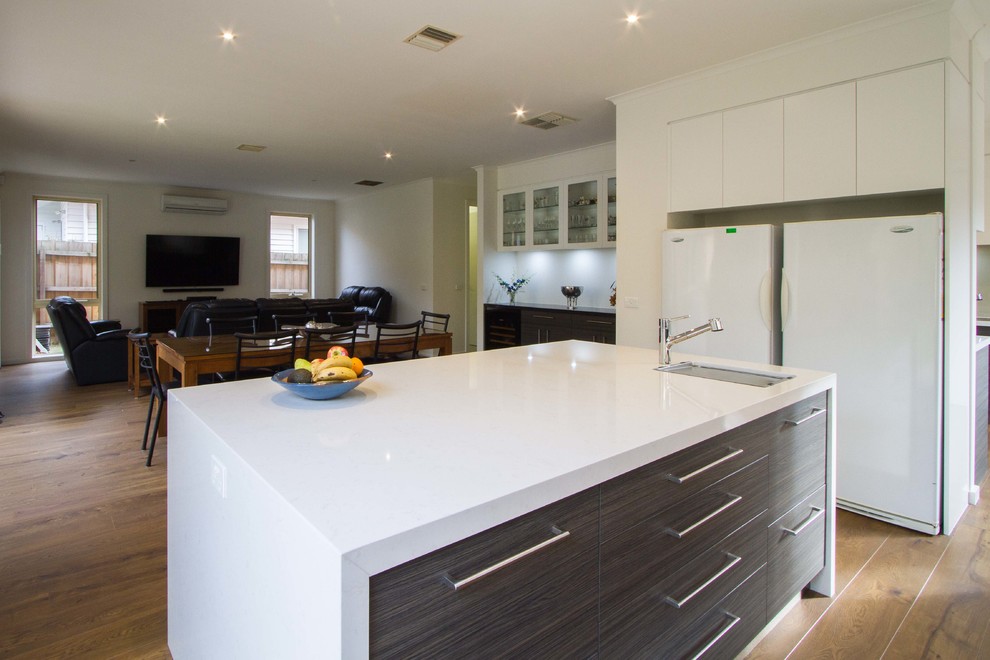 Inspiration for an expansive modern l-shaped open plan kitchen in Melbourne with an undermount sink, flat-panel cabinets, quartz benchtops, medium hardwood floors and with island.